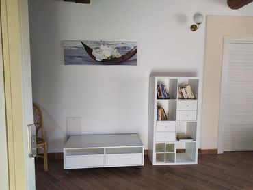 Mobili bianchi contro una parete bianca con un'opera d'arte floreale. Pavimento in legno.