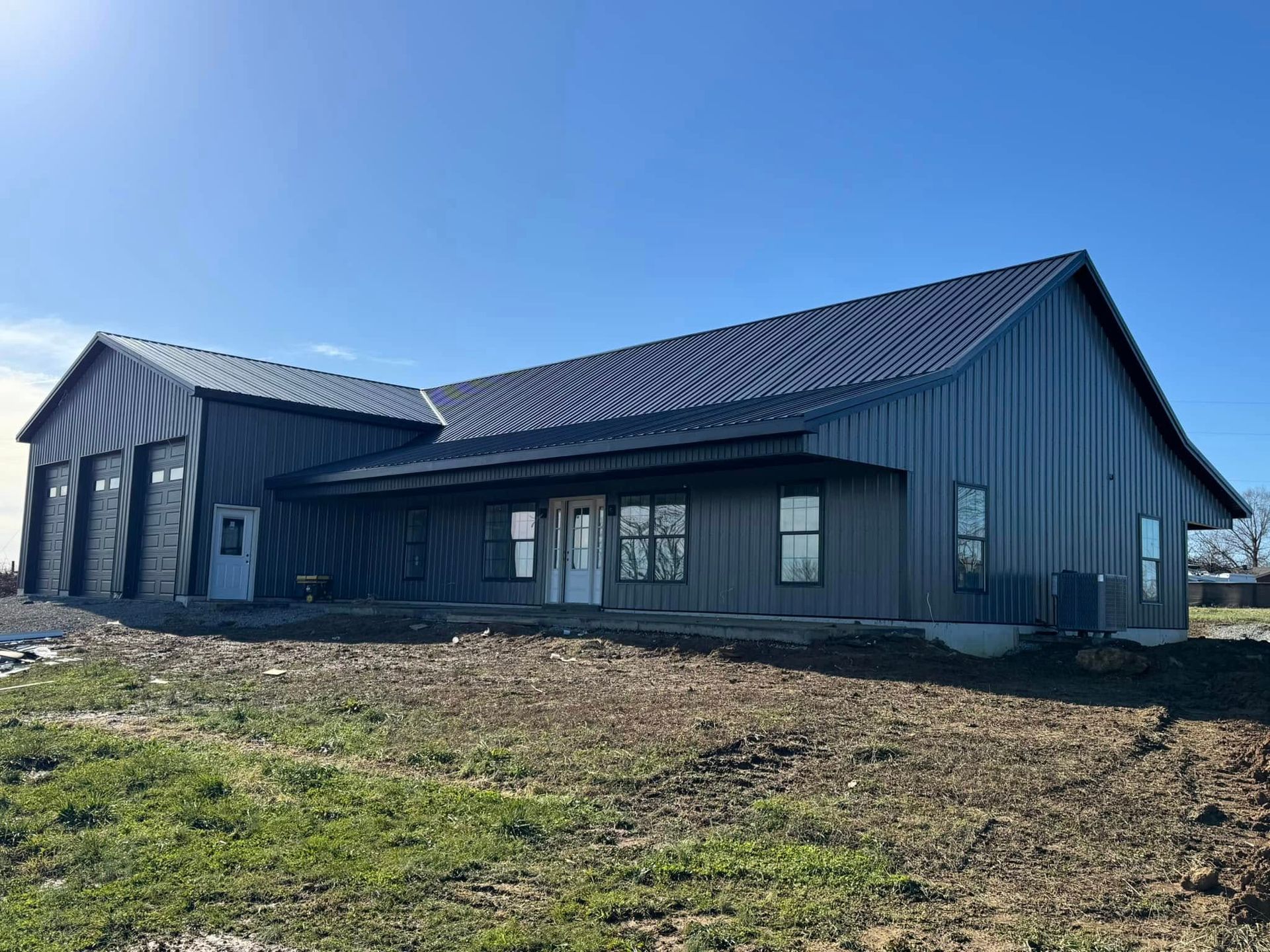 A large metal building is sitting in the middle of a grassy field.