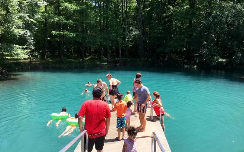 A group of people are standing on a dock near a lake.