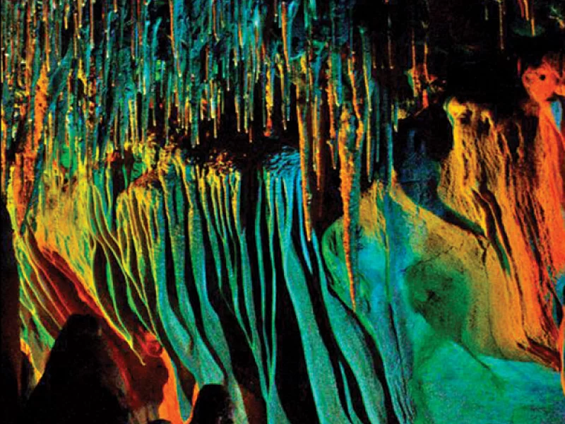 A close up of a colorful cave with icicles hanging from the ceiling.