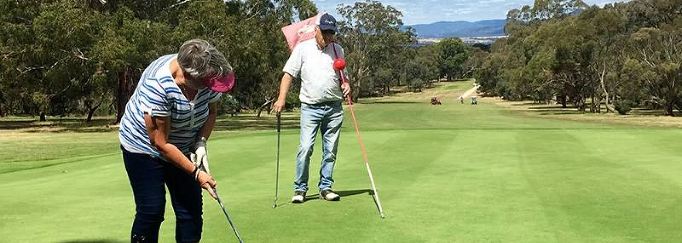 A man and a woman are playing golf on a golf course.