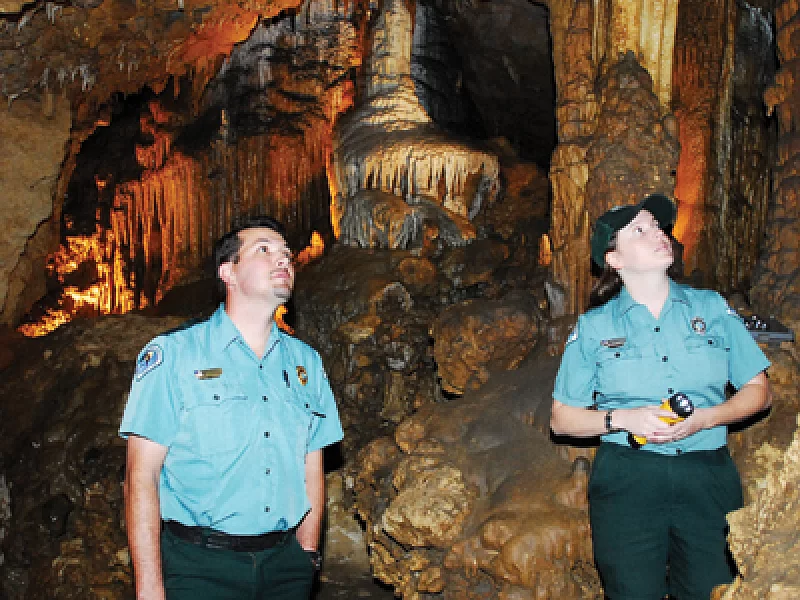 A man and a woman are looking up at a cave formation