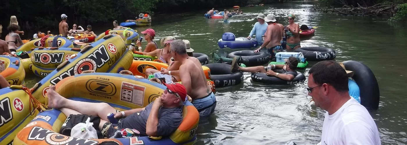 A group of people are floating down a river on inner tubes.