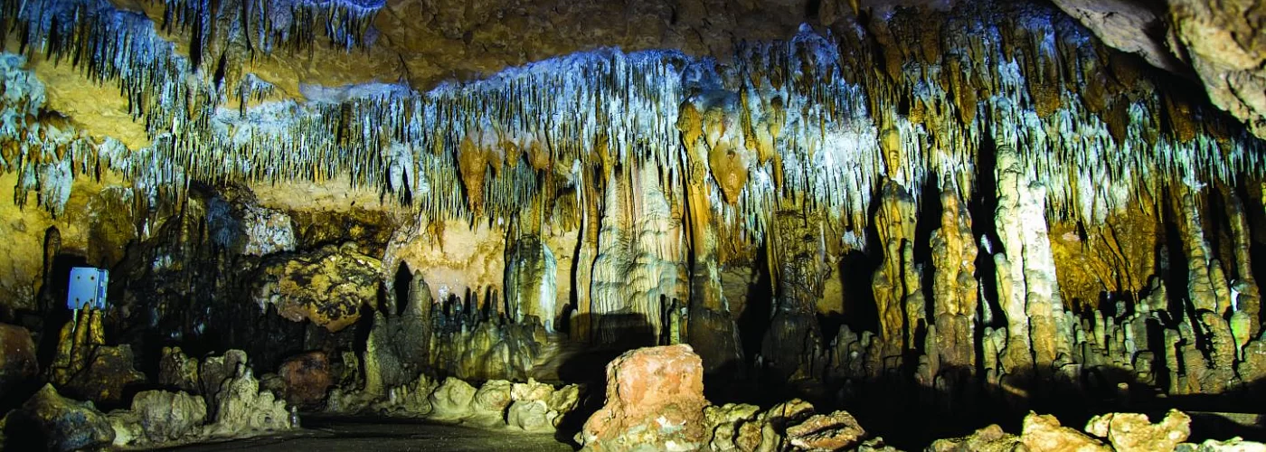 A painting of a cave with a lot of rocks hanging from the ceiling.