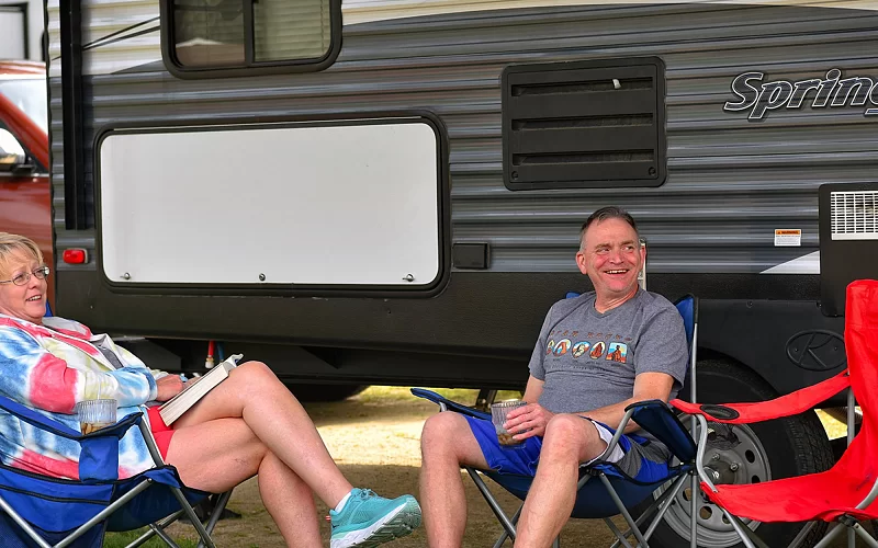A man and a woman are sitting in chairs in front of a rv.