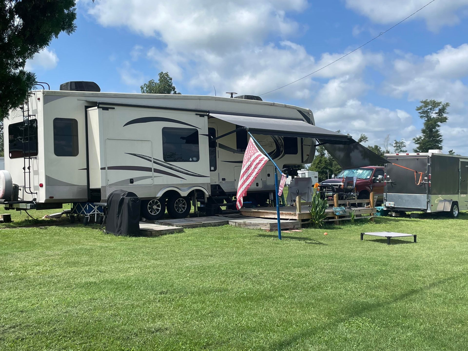 A rv is parked in a grassy field with an american flag.