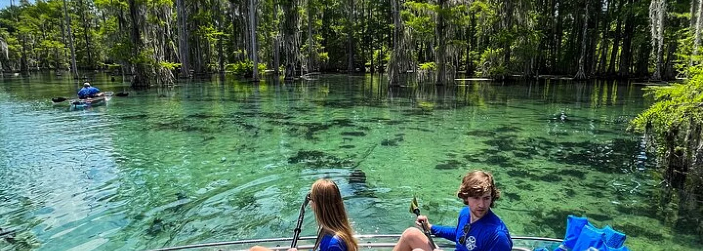 A boy and a girl are sitting in a kayak on a lake.