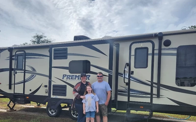 A family is standing in front of a rv.