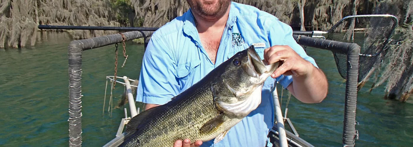 A man is holding a large fish in his hands on a boat.