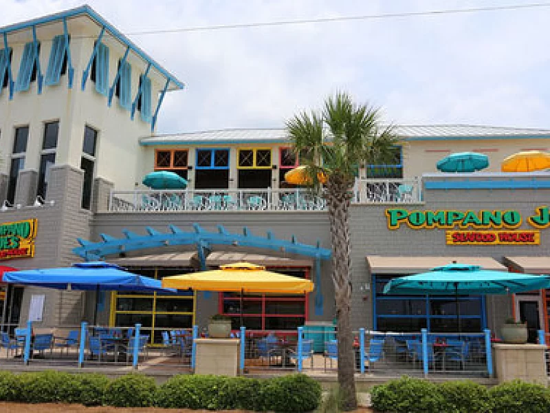 A restaurant with umbrellas and chairs in front of it.