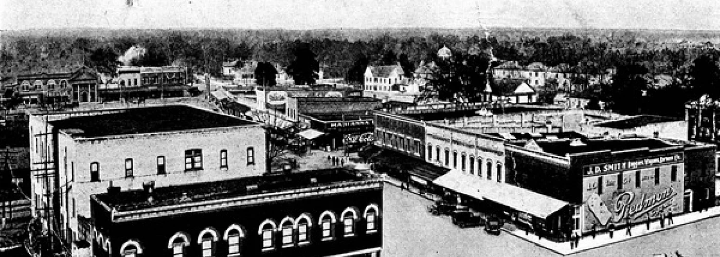 A black and white photo of a city with buildings and trees