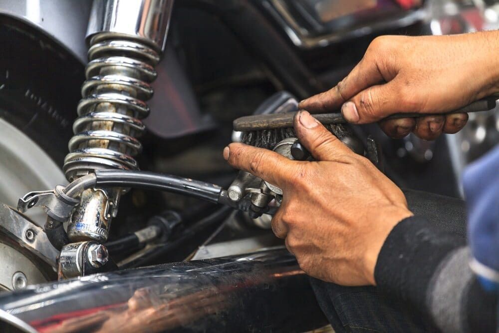 A Person is Cleaning a Motorcycle With a Brush — Fosters Ace Auto Repairs In Aitkenvale, QLD