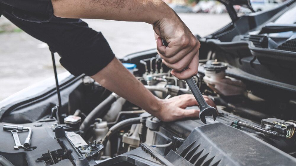 A Man is Working on the Engine of a Car With a Wrench — Fosters Ace Auto Repairs In Aitkenvale, QLD