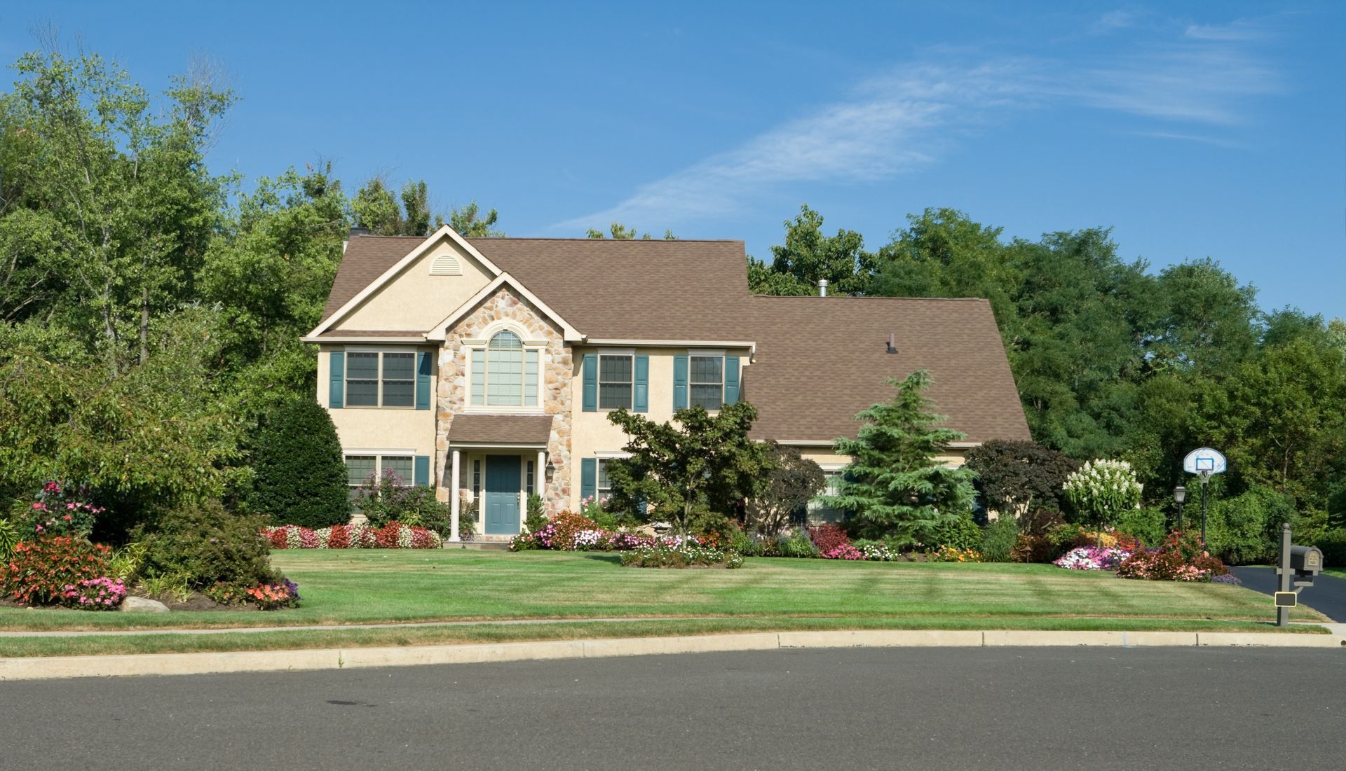 Two-story beige house with a brown roof and a well-manicured lawn on a sunny day. Two-story beige house with a brown roof and a well-manicured lawn on a sunny day.