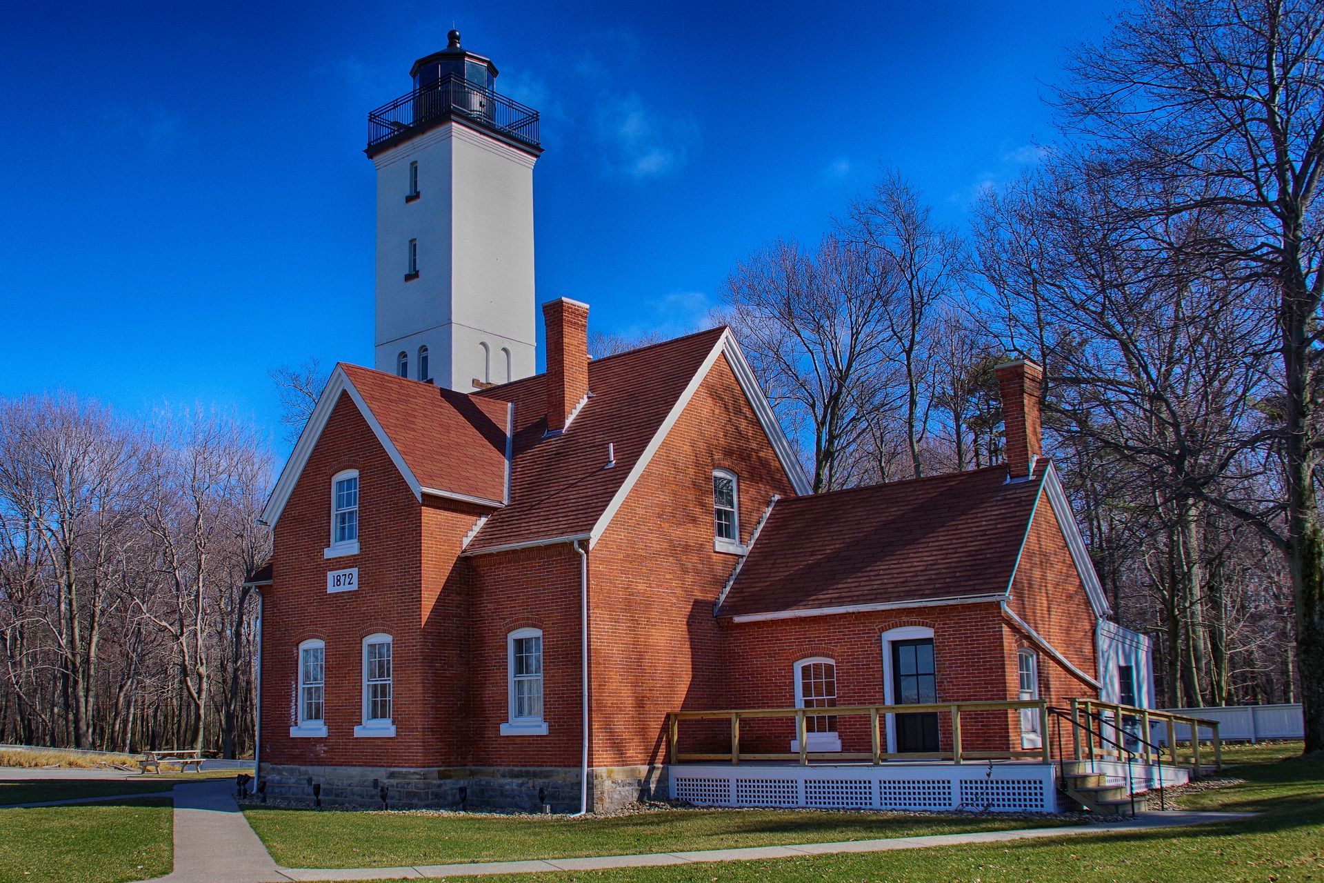 Brick lighthouse with a tall white tower, against a clear blue sky. Brick lighthouse with a tall white tower, against a clear blue sky.