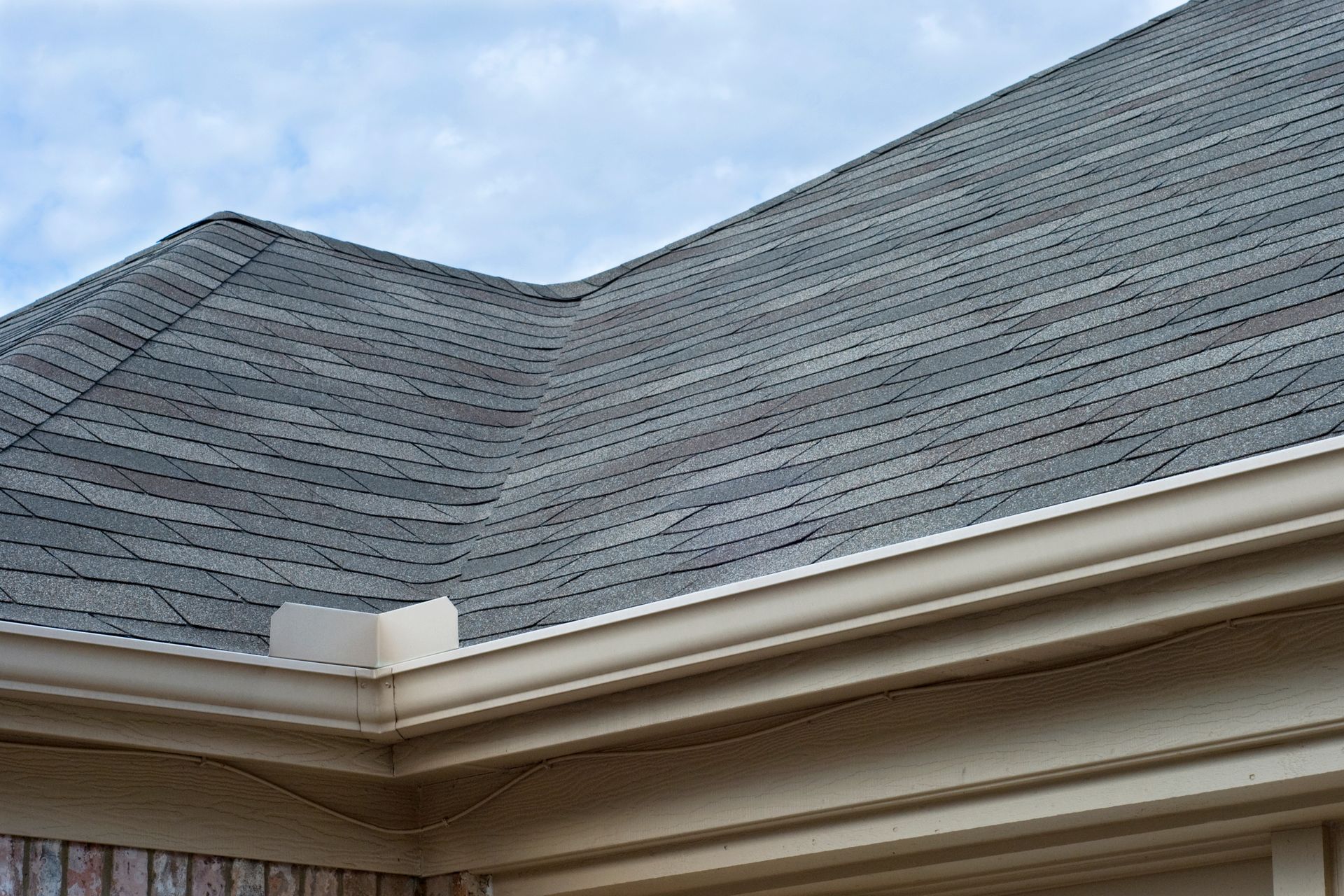 Person installing a white downspout into a roof gutter on a building with a green metal roof. Person installing a white downspout into a roof gutter on a building with a green metal roof.