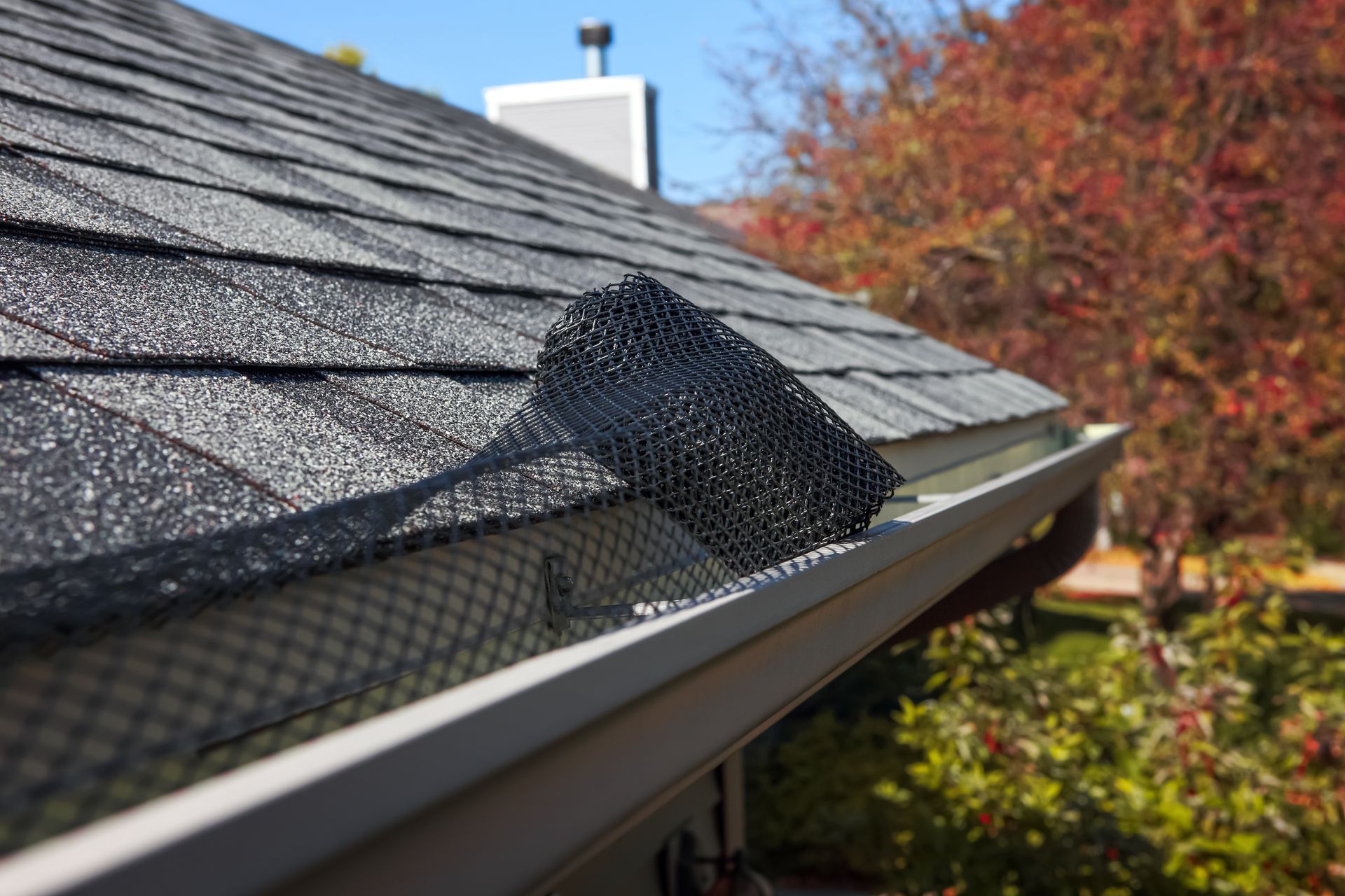Gutter with black mesh cover installed on a rooftop to prevent debris buildup. Gutter with black mesh cover installed on a rooftop to prevent debris buildup.