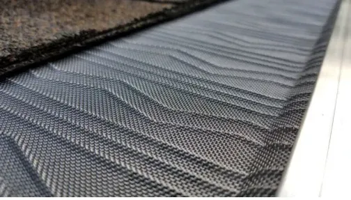 Leaves in a gutter with a mesh guard, brown and green grass in background. Leaves in a gutter with a mesh guard, brown and green grass in background.