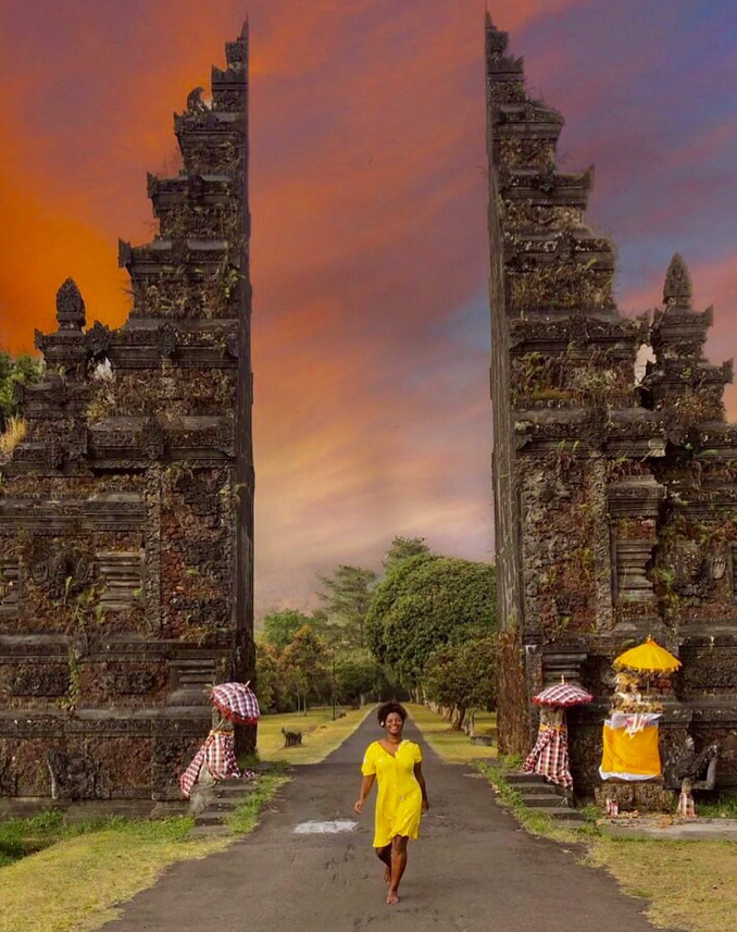 A woman in a yellow dress is walking down a road.