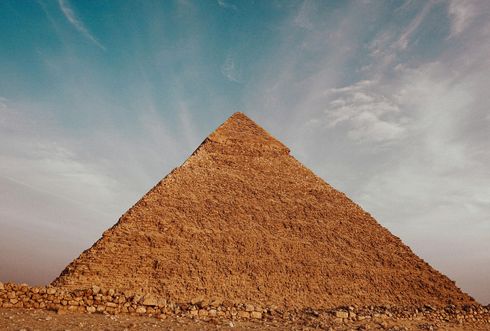 A large pyramid against a blue sky with clouds.