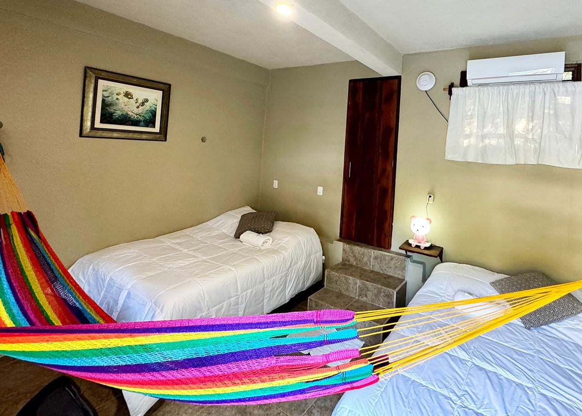 A hotel room with two beds and a colorful hammock.