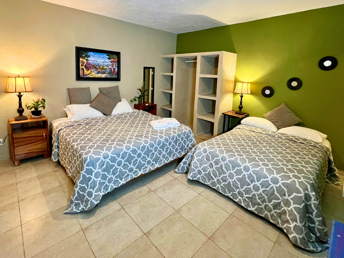 A hotel room with two beds and a green wall