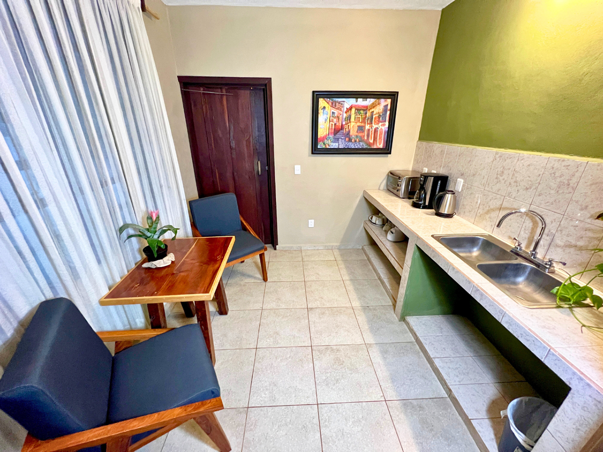 A kitchen with two sinks , a chair , a table and a picture on the wall.