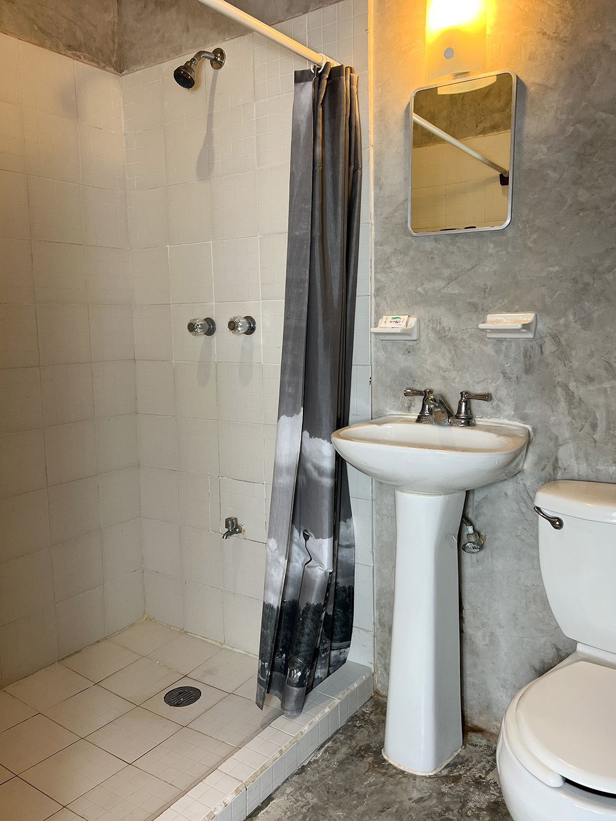 A bathroom with a sink , toilet , shower and mirror