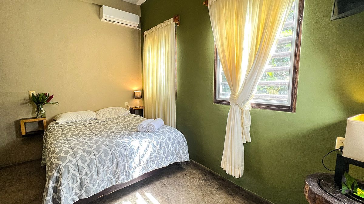 A hotel room with a bed and a window with curtains.