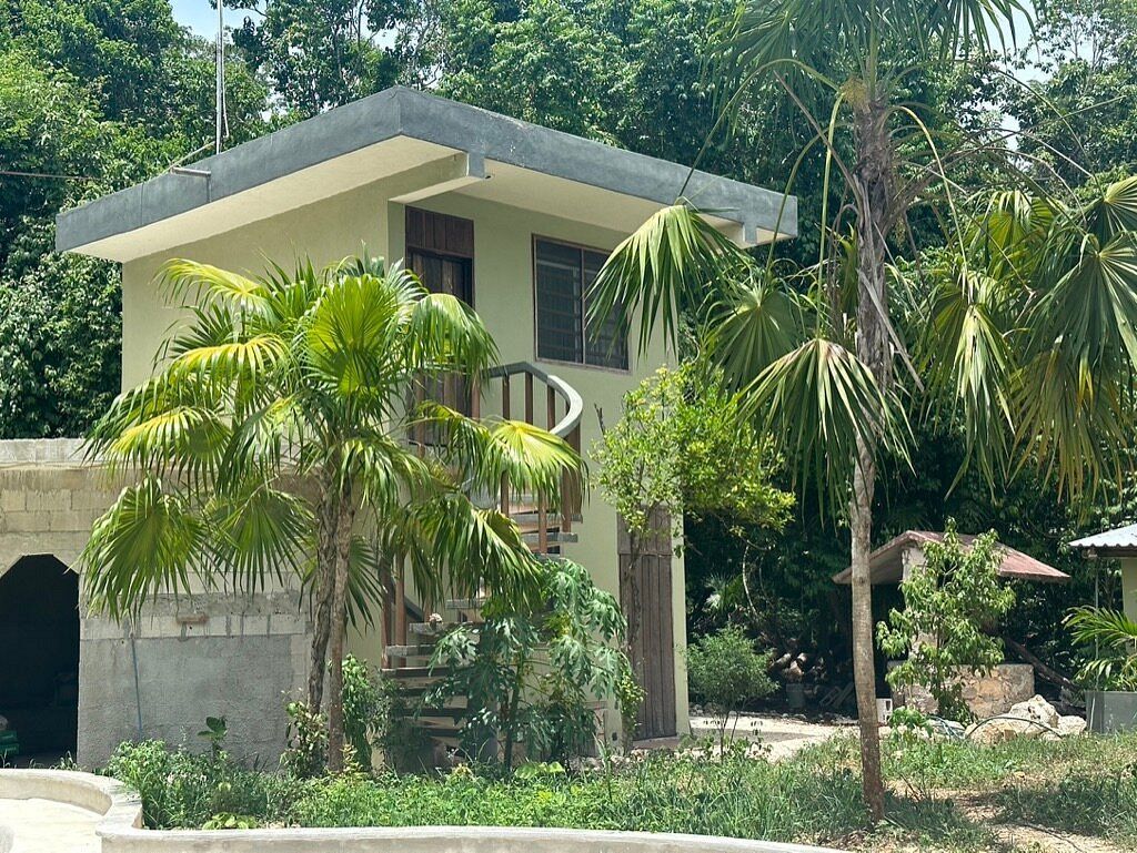 Hotel rooms with a spiral staircase, surrounded by palm trees.