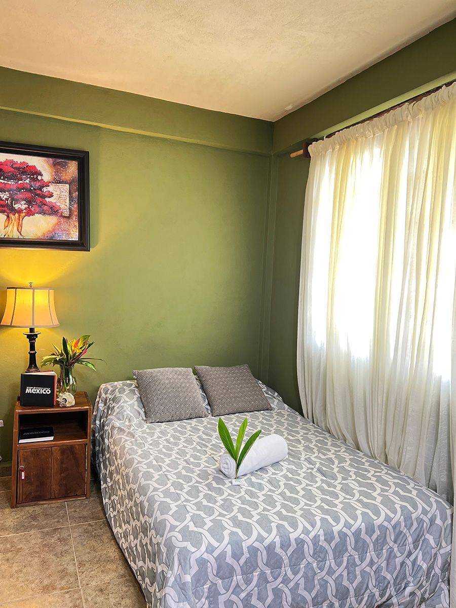 A hotel room with a bed , nightstand , lamp and painting on the wall.