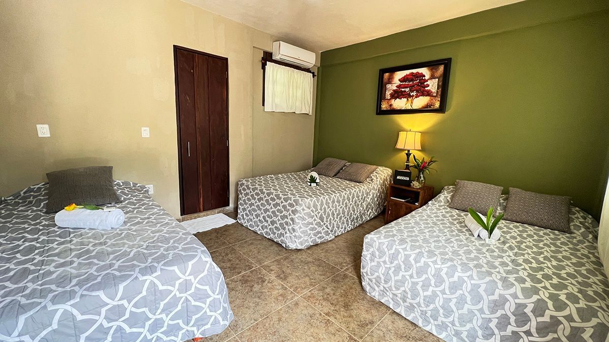 A hotel room with three beds.