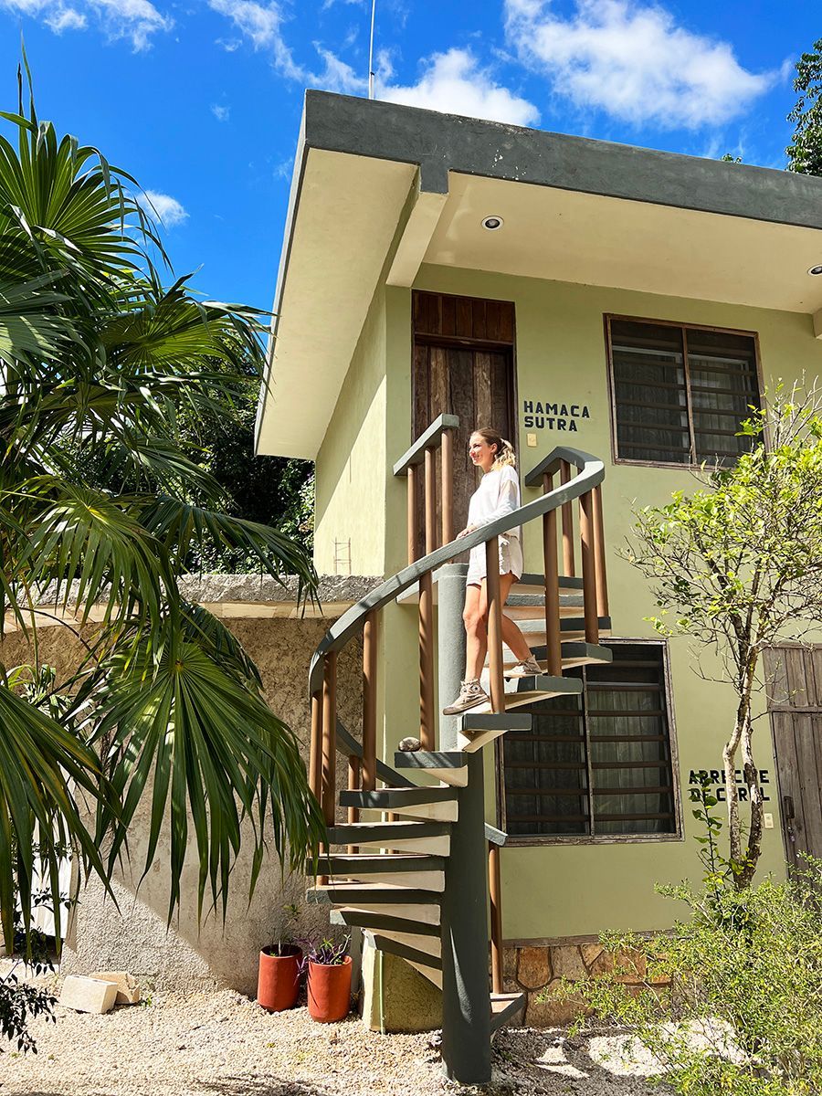 A woman is standing on the stairs of a hotel building.