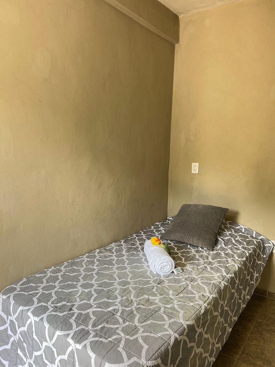 A hotel room with a single bed and a pillow.