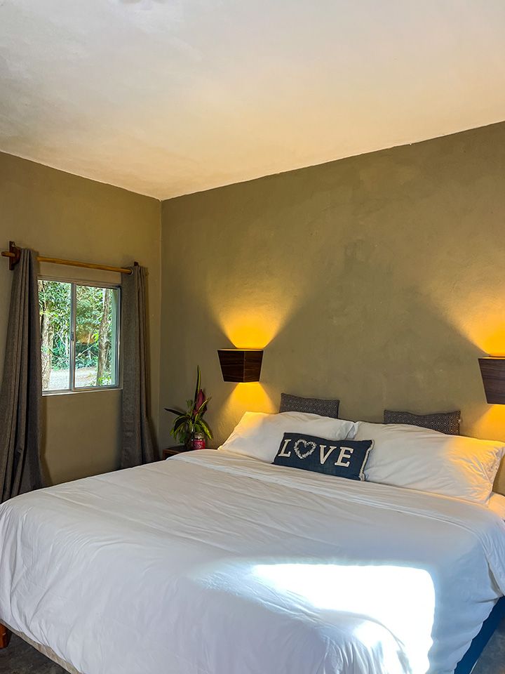 A hotel suite with a king size bed and a love pillow on the bed.