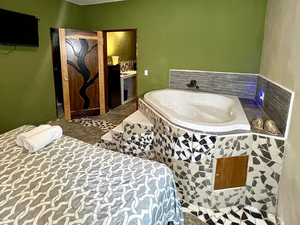 A hotel suite with a jacuzzi tub and a bed.