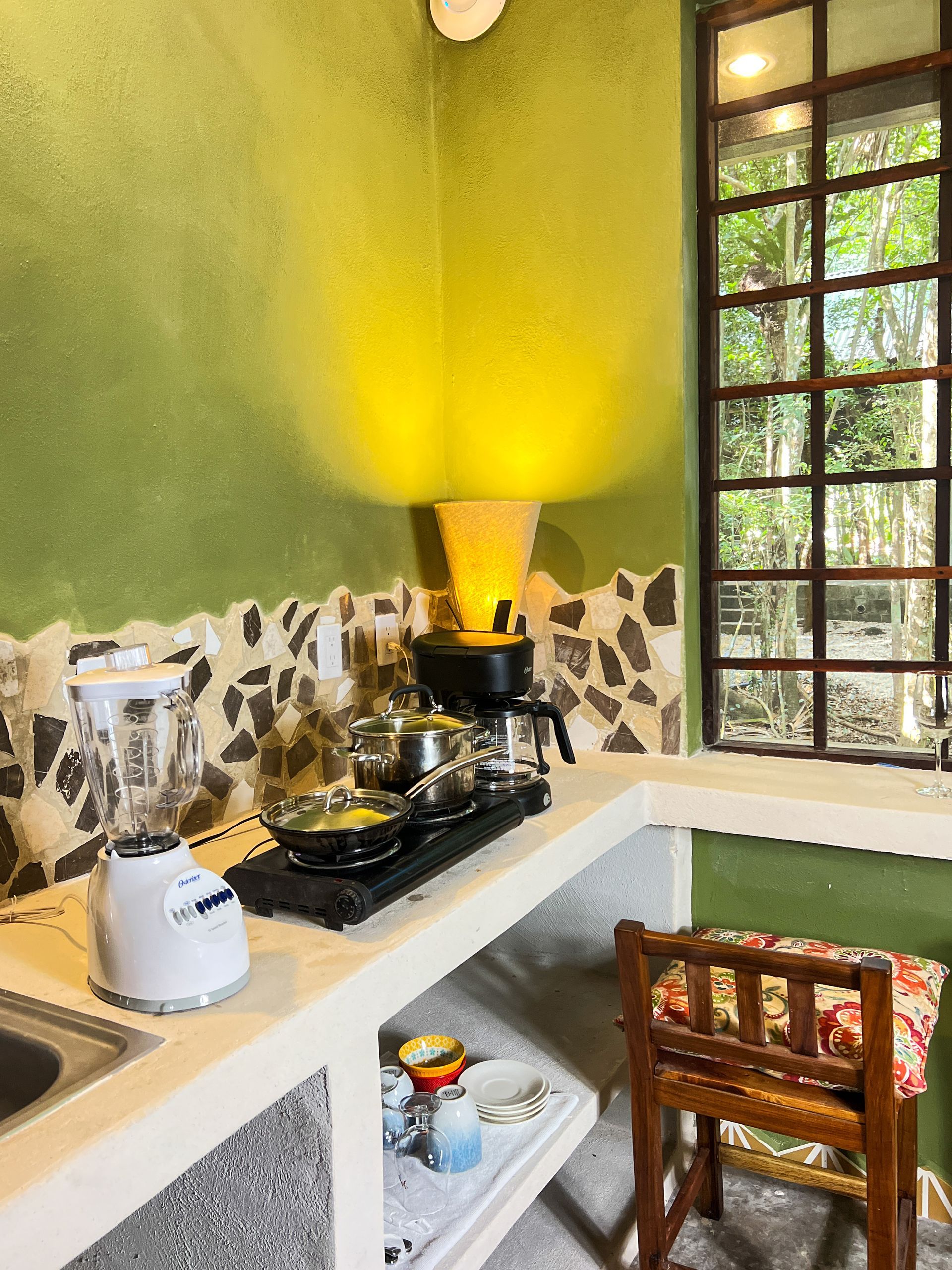 A kitchen with a blender , coffee maker , pots and pans on the counter.