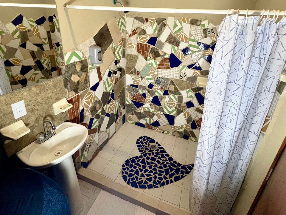 A bathroom with a sink and a shower with a tile heart on the floor.