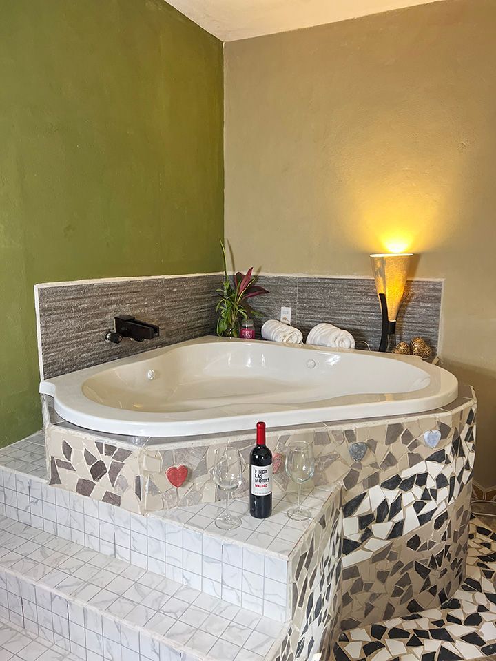 A room with a jacuzzi tub and a bottle of wine