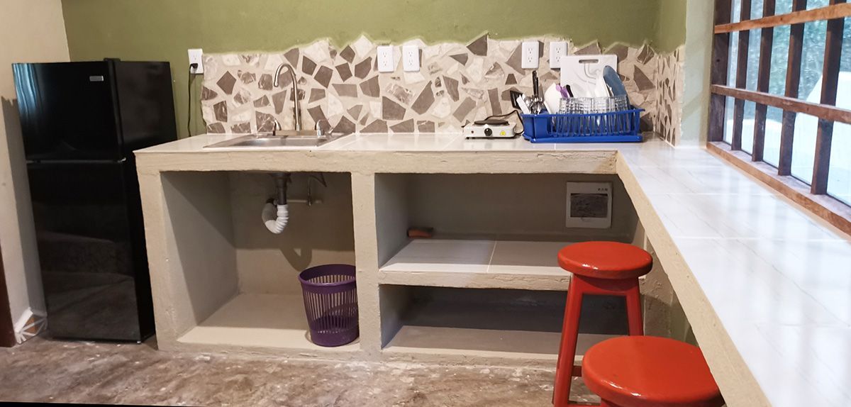 A kitchen with a refrigerator , sink , and two red stools.