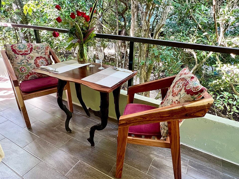 A balcony with two chairs and a table with a vase of flowers on it.