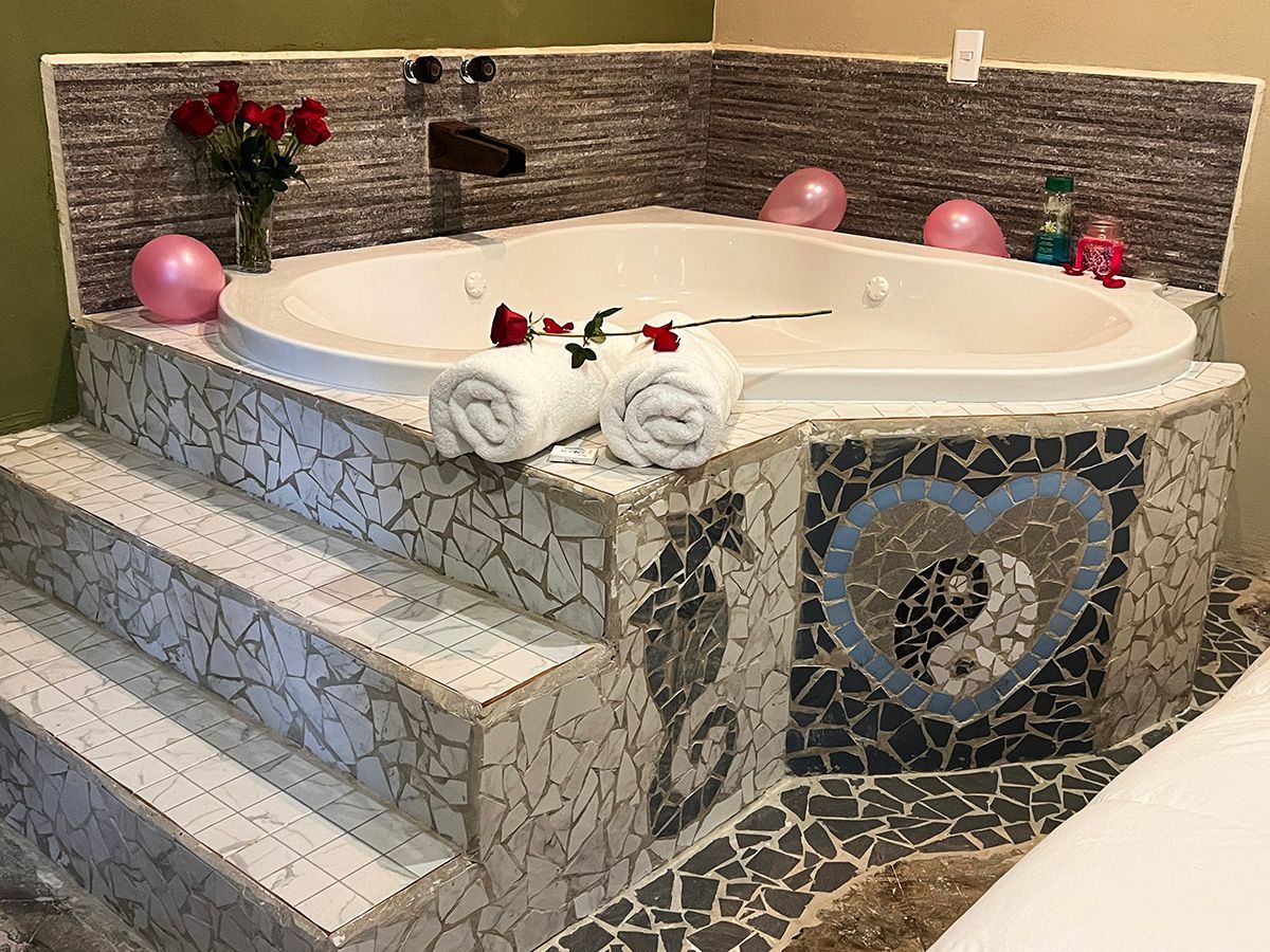 A hotel suite with a large jacuzzi tub and stairs leading up to it.