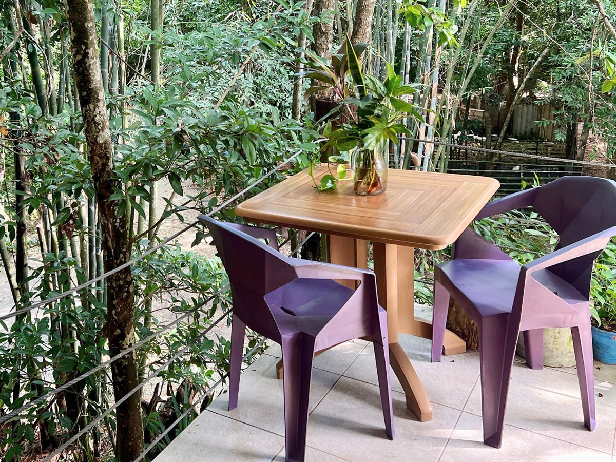 A table and chairs on a balcony with trees in the background.