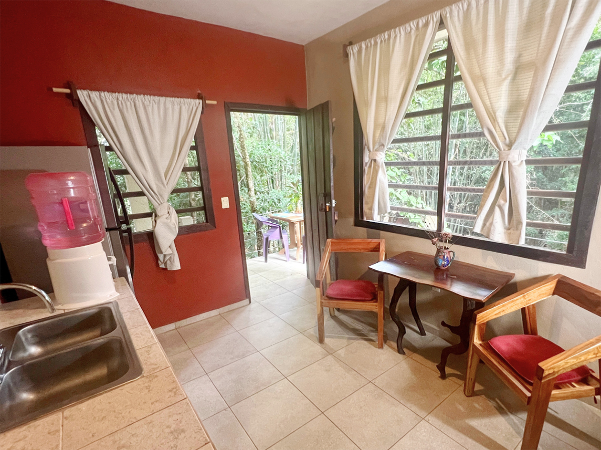 A kitchen with a sink , chairs , table and window.