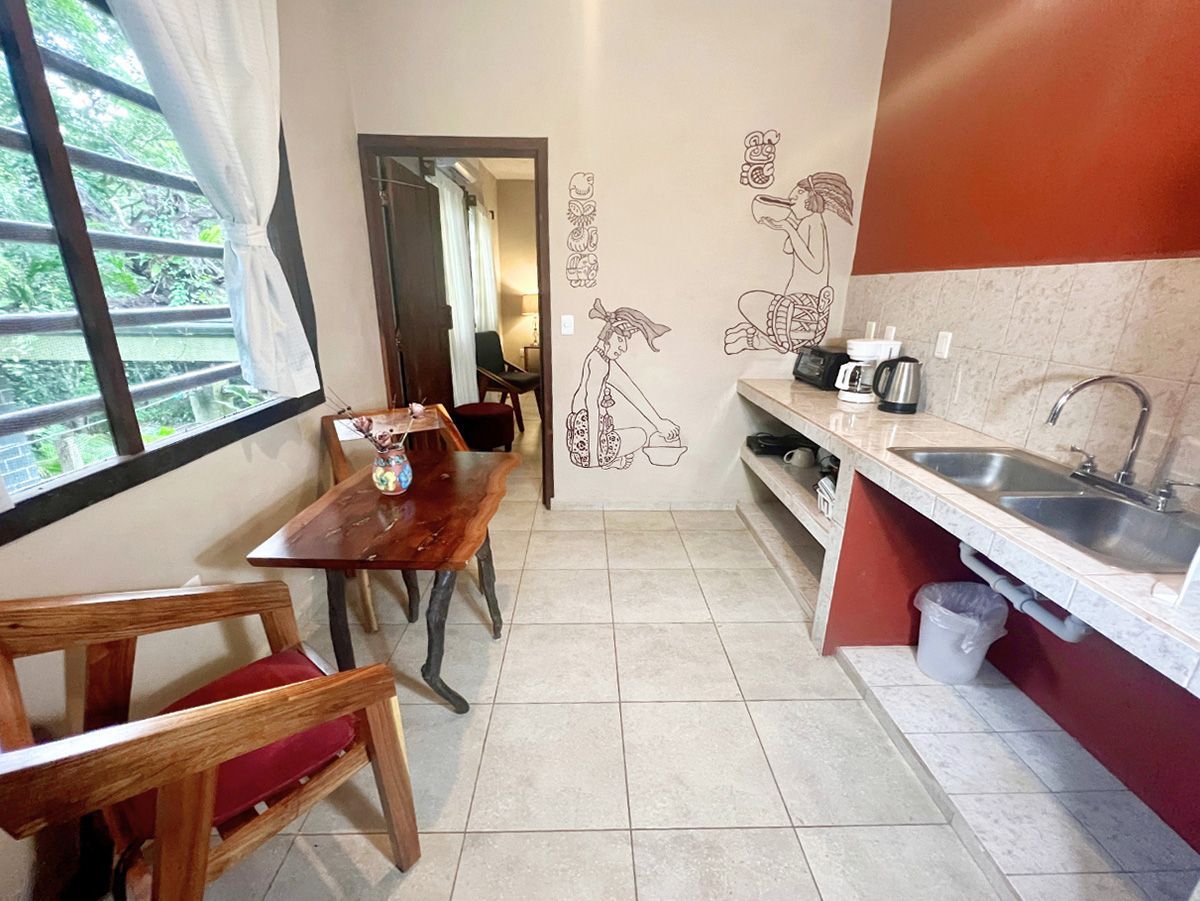 A kitchen with a sink , table , chairs and a window.