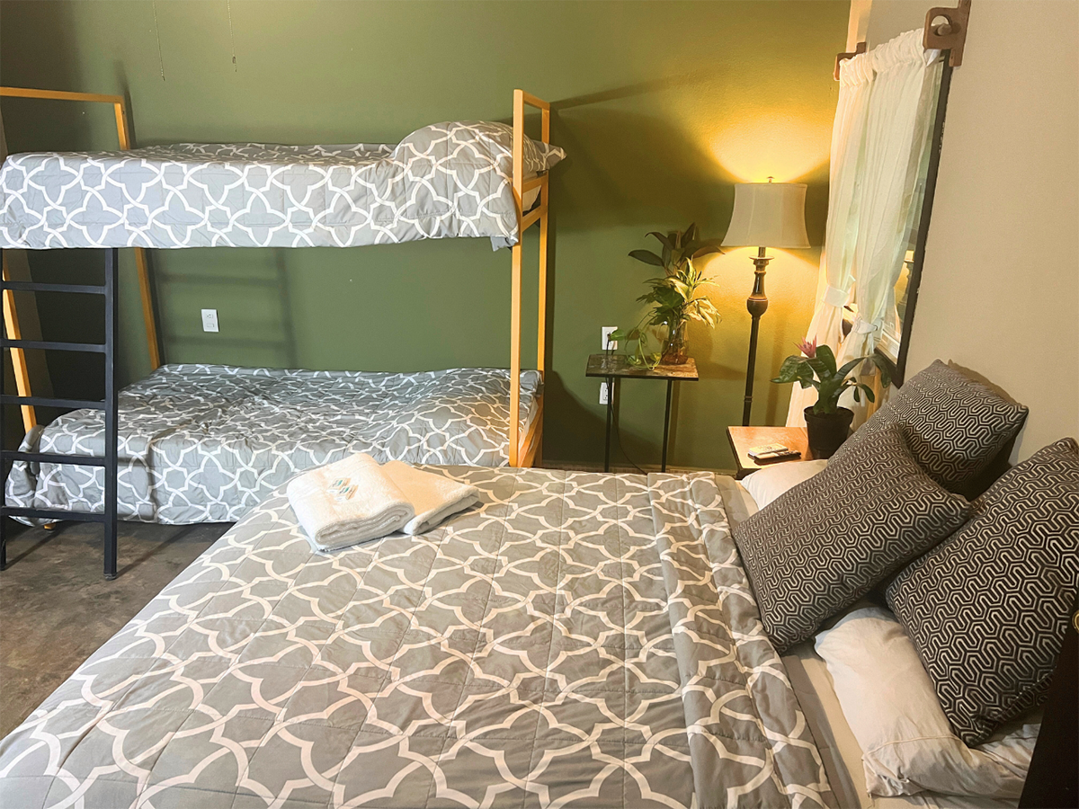A hotel room with a bunk bed , a bed , and a lamp.