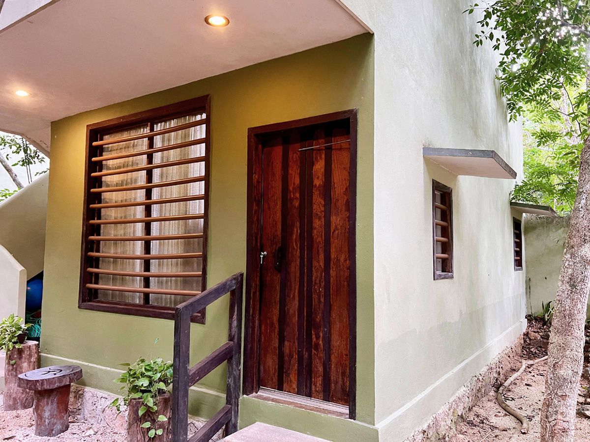 A small green hotel building with a wooden door and window.