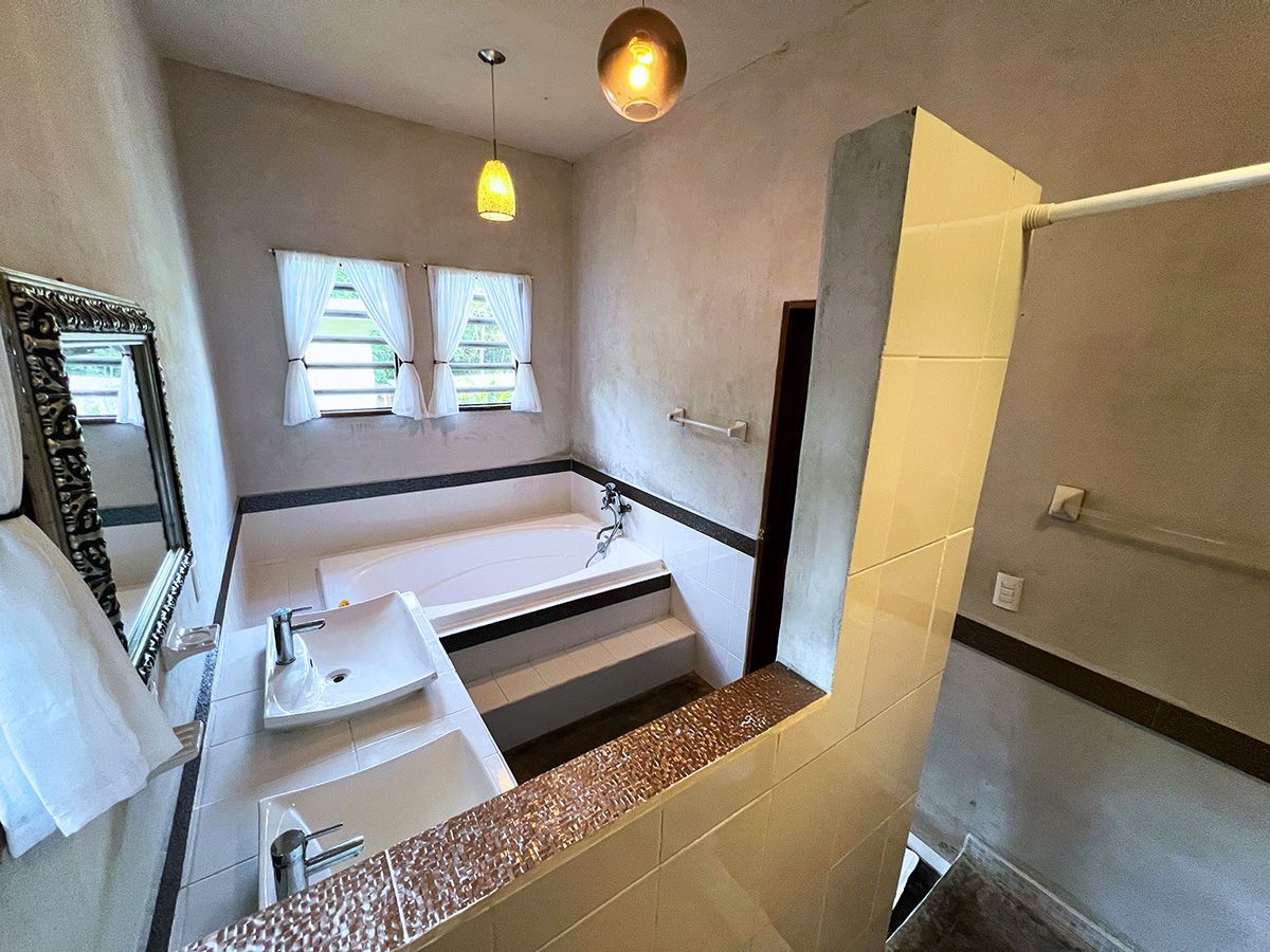 A bathroom with a tub , sink and mirror.