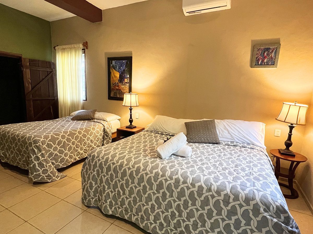 A hotel room with two beds and two lamps.