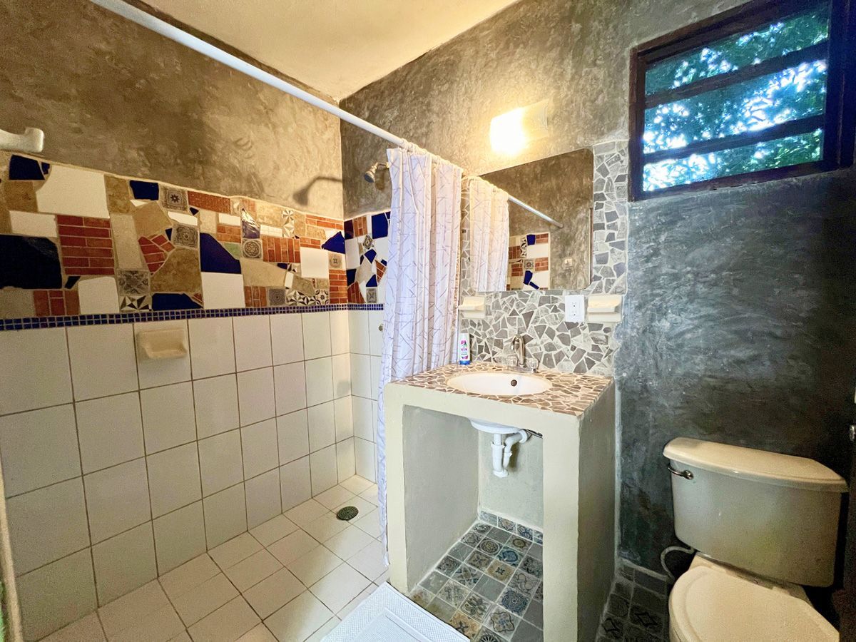 A bathroom with a toilet , sink and shower.